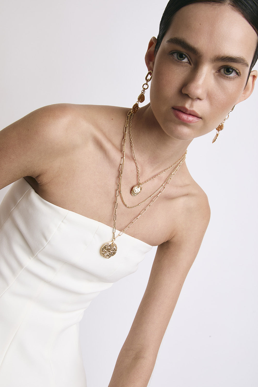 Una chica usando tres collares y aretes Join.