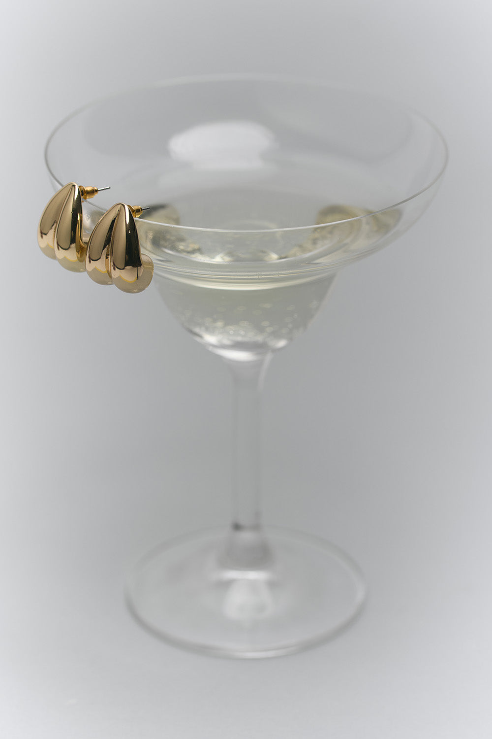 Un par de aretes apoyados sobre una copa de martini. 